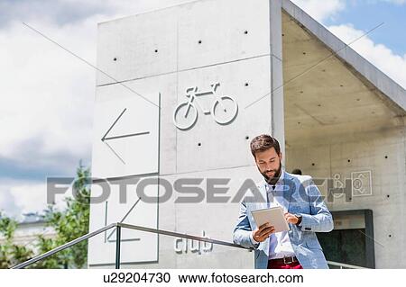 Portrait of young attractive businessman using digital tablet outdoors View Large Photo Image Stock Image - Portrait of young attractive businessman using digital tablet outdoors. Fotosearch