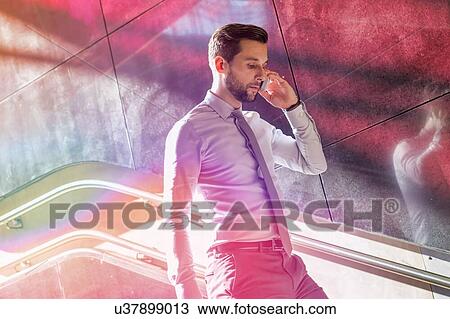 Portrait of young attractive businessman talking on smartphone while walking downstairs View Large Photo Image Stock Image - Portrait of young attractive businessman talking on smartphone while walking downstairs. Fotosearch