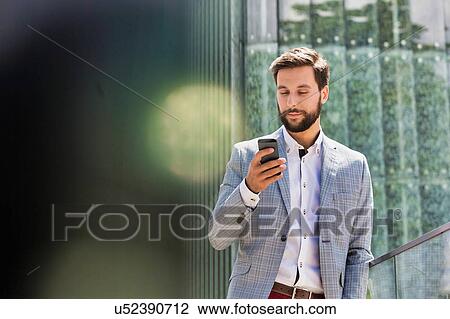 Stock Image - Portrait of young attractive businessman using smartphone. Fotosearch