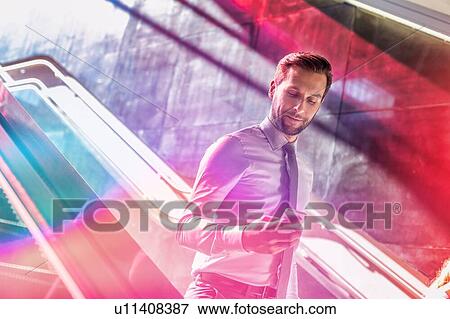 Portrait of young attractive businessman using smartphone while walking downstairs View Large Photo Image Stock Photo - Portrait of young attractive businessman using smartphone while walking downstairs. Fotosearch