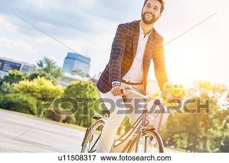 Stock Photo - Portrait of young attractive businessman riding bicycle . Fotosearch