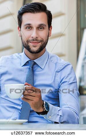 Portrait of young attractive businessman sitting in cafe while drinking coffee View Large Photo Image Stock Photo - Portrait of young attractive businessman sitting in cafe while drinking coffee . Fotosearch