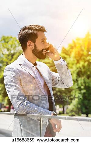 Portrait of young attractive businessman talking on smartphone View Large Photo Image Stock Photo - Portrait of young attractive businessman talking on smartphone. Fotosearch