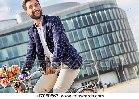 Stock Photo - Portrait of young attractive businessman riding bicycle . Fotosearch