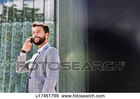 Stock Photo - Portrait of young attractive businessman talking on smartphone. Fotosearch