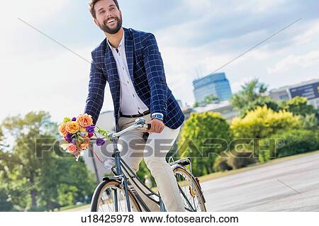 Stock Photo - Portrait of young attractive businessman riding bicycle . Fotosearch