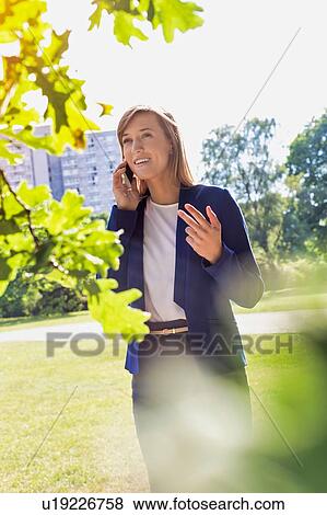 Stock Photo - Portrait of young attractive businesswoman talking on smartphone in park. Fotosearch