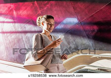 Portrait of young attractive businesswoman using smartphone while walking downstairs View Large Photo Image Stock Photo - Portrait of young attractive businesswoman using smartphone while walking downstairs. Fotosearch