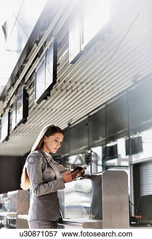 Stock Photo - Portrait of young attractive businesswoman looking at her passport in airport. Fotosearch