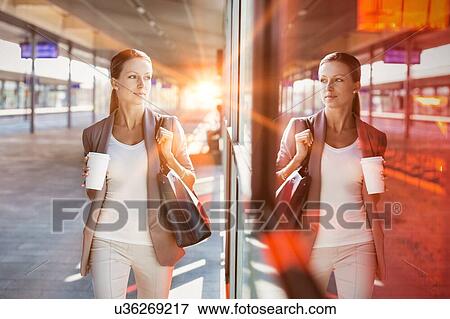 Portrait of young attractive businesswoman holding cup of coffee while walking View Large Photo Image Stock Photo - Portrait of young attractive businesswoman holding cup of coffee while walking. Fotosearch