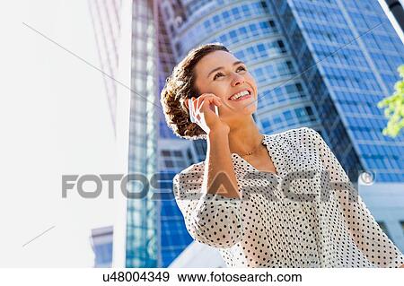 Stock Photo - Portrait of young attractive businesswoman smiling while talking on smartphone . Fotosearch