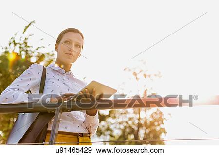 Portrait of young attractive businesswoman using digital tablet while leaning on railing View Large Photo Image Stock Photo - Portrait of young attractive businesswoman using digital tablet while leaning on railing. Fotosearch