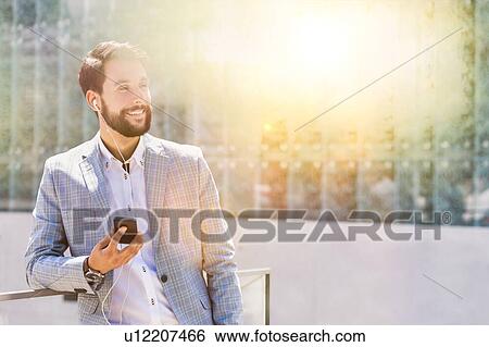 Portrait of young attractive businessman using smartphone with earphones on View Large Photo Image Stock Photograph - Portrait of young attractive businessman using smartphone with earphones on. Fotosearch
