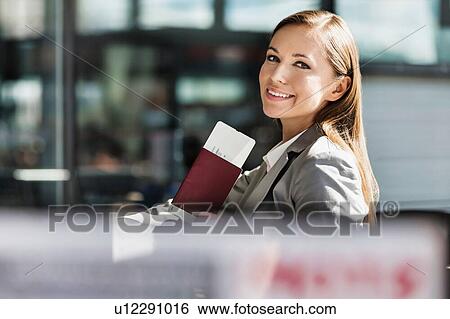 Portrait of young attractive businesswoman holding her passport and boarding pass in airport View Large Photo Image Stock Photograph - Portrait of young attractive businesswoman holding her passport and boarding pass in airport. Fotosearch
