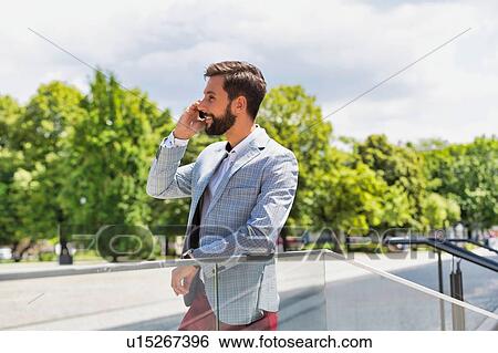 Portrait of young attractive businessman talking on smartphone View Large Photo Image Stock Photograph - Portrait of young attractive businessman talking on smartphone. Fotosearch