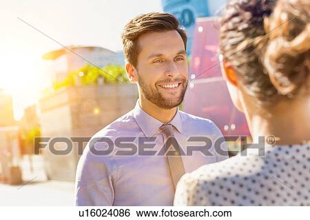 Stock Photograph - Portrait of young attractive businessman smiling while talking to businesswoman. Fotosearch