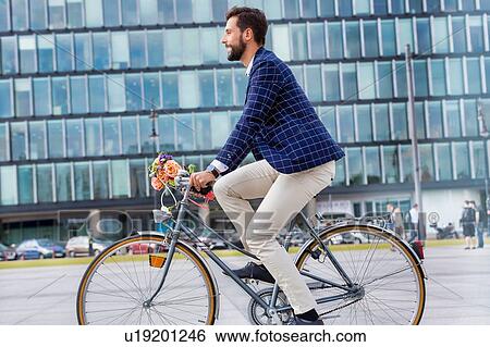 Stock Photograph - Portrait of young attractive businessman riding bicycle . Fotosearch