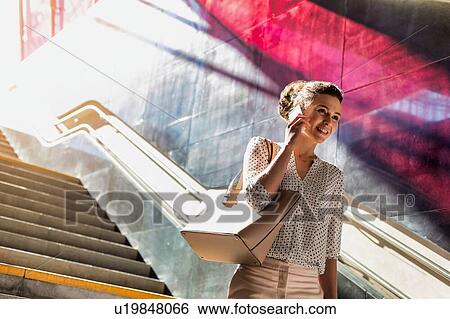 Portrait of young attractive businesswoman talking on smartphone while walking downstairs View Large Photo Image Stock Photograph - Portrait of young attractive businesswoman talking on smartphone while walking downstairs. Fotosearch