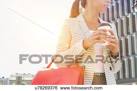 Portrait of young attractive businesswoman smiling while holding a cup of coffee outside office building View Large Photo Image Stock Photograph - Portrait of young attractive businesswoman smiling while holding a cup of coffee outside office building. Fotosearch