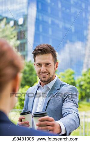 Portrait of young attractive businessman giving coffee to businesswoman View Large Photo Image Stock Photograph - Portrait of young attractive businessman giving coffee to businesswoman . Fotosearch
