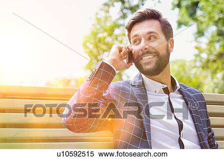 Stock Photography - Portrait of young attractive businessman smiling while talking on smartphone. Fotosearch