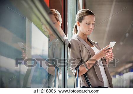 Portrait of young attractive businesswoman using smartphone while leaning on window View Large Photo Image Stock Photography - Portrait of young attractive businesswoman using smartphone while leaning on window. Fotosearch