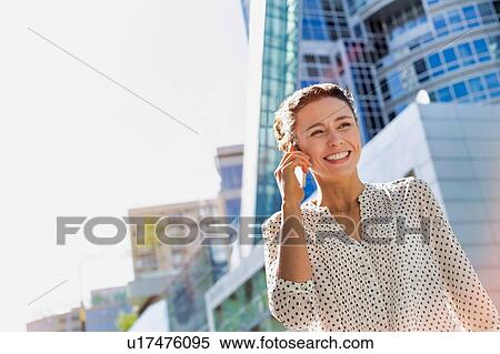 Stock Photography - Portrait of young attractive businesswoman smiling while talking on smartphone . Fotosearch