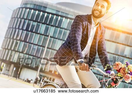 Stock Photography - Portrait of young attractive businessman riding bicycle . Fotosearch