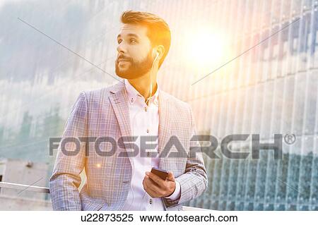 Portrait of young attractive businessman using smartphone with earphones on View Large Photo Image Stock Photography - Portrait of young attractive businessman using smartphone with earphones on. Fotosearch