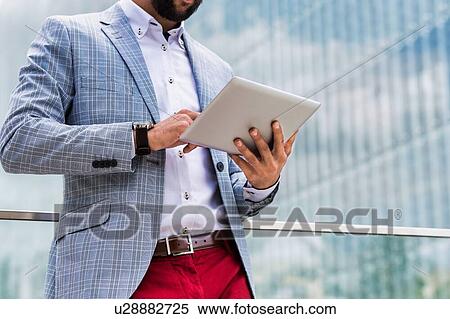 Portrait of young attractive businessman using digital tablet outdoors with yellow lens flare View Large Photo Image Stock Photography - Portrait of young attractive businessman using digital tablet outdoors with yellow lens flare. Fotosearch