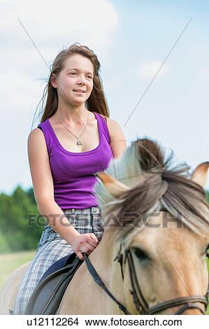 Picture - Portrait of young attractive woman riding horse in ranch. Fotosearch