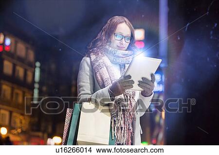 Portrait of young attractive woman smiling and using digital tablet while on night shopping View Large Photo Image Picture - Portrait of young attractive woman smiling and using digital tablet while on night shopping. Fotosearch