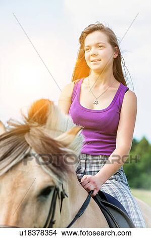 Picture - Portrait of young attractive woman riding horse in ranch. Fotosearch
