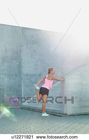 Portrait of young attractive woman stretching her legs View Large Photo Image Stock Image - Portrait of young attractive woman stretching her legs. Fotosearch