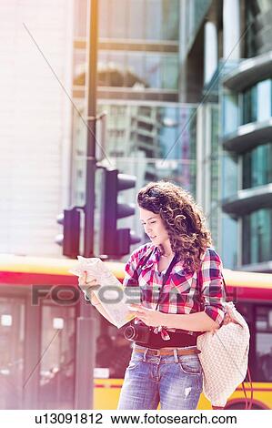 Portrait of young attractive woman looking on the map in the city with lens flare in background View Large Photo Image Stock Image - Portrait of young attractive woman looking on the map in the city with lens flare in background. Fotosearch