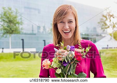 Stock Image - Portrait of young attractive woman holding boquet of flowers. Fotosearch