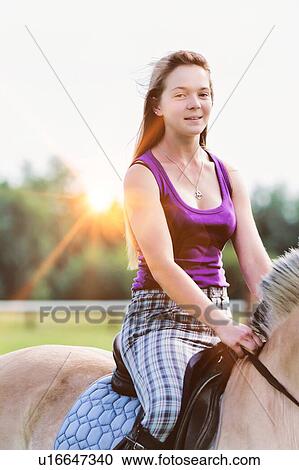 Stock Image - Portrait of young attractive woman riding horse in ranch. Fotosearch