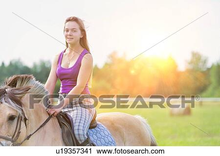 Stock Image - Portrait of young attractive woman riding horse in ranch. Fotosearch