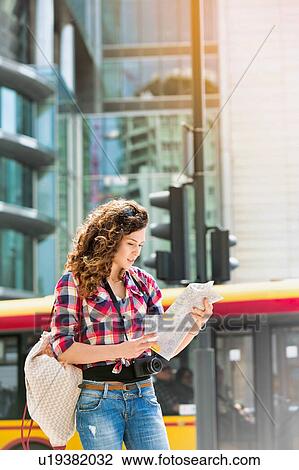 Stock Image - Portrait of young attractive woman looking on the map in the city. Fotosearch