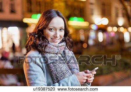 Portrait of young attractive woman smiling while using smartphone View Large Photo Image Stock Image - Portrait of young attractive woman smiling while using smartphone. Fotosearch