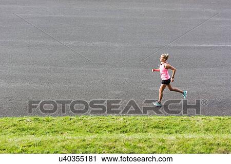 Stock Image - Portrait of young attractive woman running in park. Fotosearch