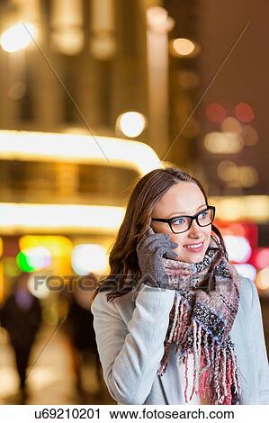 Portrait of young attractive woman smiling and talking on smartphone while holding paper bags at night shopping View Large Photo Image Stock Image - Portrait of young attractive woman smiling and talking on smartphone while holding paper bags at night shopping. Fotosearch