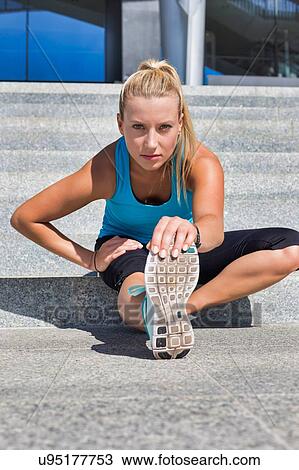 Stock Image - Portrait of young attractive woman stretching her legs. Fotosearch