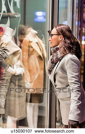 Portrait of young attractive woman looking at the dress on a manequin in shop through the window View Large Photo Image Stock Photo - Portrait of young attractive woman looking at the dress on a manequin in shop through the window. Fotosearch