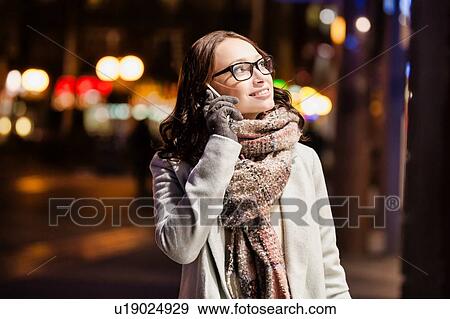 Portrait of young attractive woman talking on smartphone at night shopping View Large Photo Image Stock Photo - Portrait of young attractive woman talking on smartphone at night shopping. Fotosearch