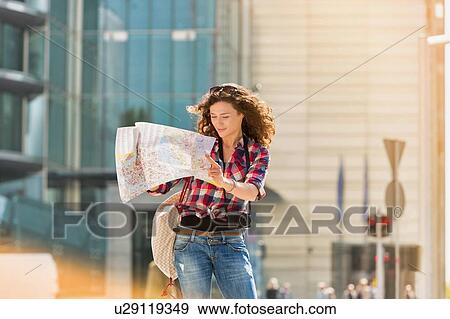 Stock Photo - Portrait of young attractive woman looking on the map in the city. Fotosearch