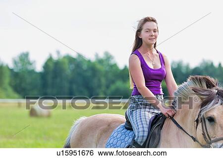 Stock Photograph - Portrait of young attractive woman riding horse in ranch. Fotosearch