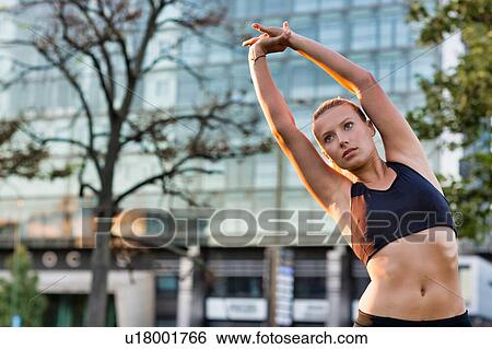 Stock Photograph - Portrait of young attractive woman stretching in park. Fotosearch