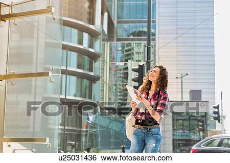 Stock Photograph - Portrait of young attractive woman looking on the map in the city. Fotosearch