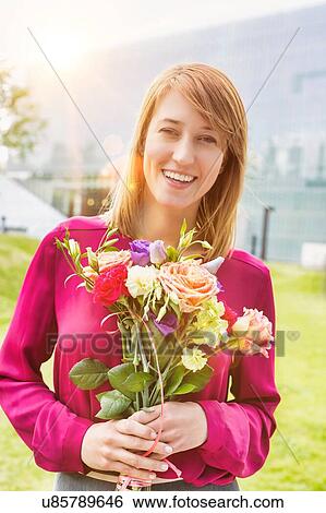 Stock Photograph - Portrait of young attractive woman holding boquet of flowers. Fotosearch